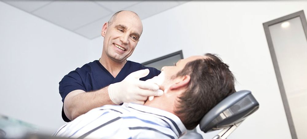 Dr. Knop untersucht einen Patienten im Behandlungszimmer